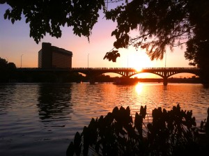 People viewing bats from bridge over river at sunset in Austin, Texas